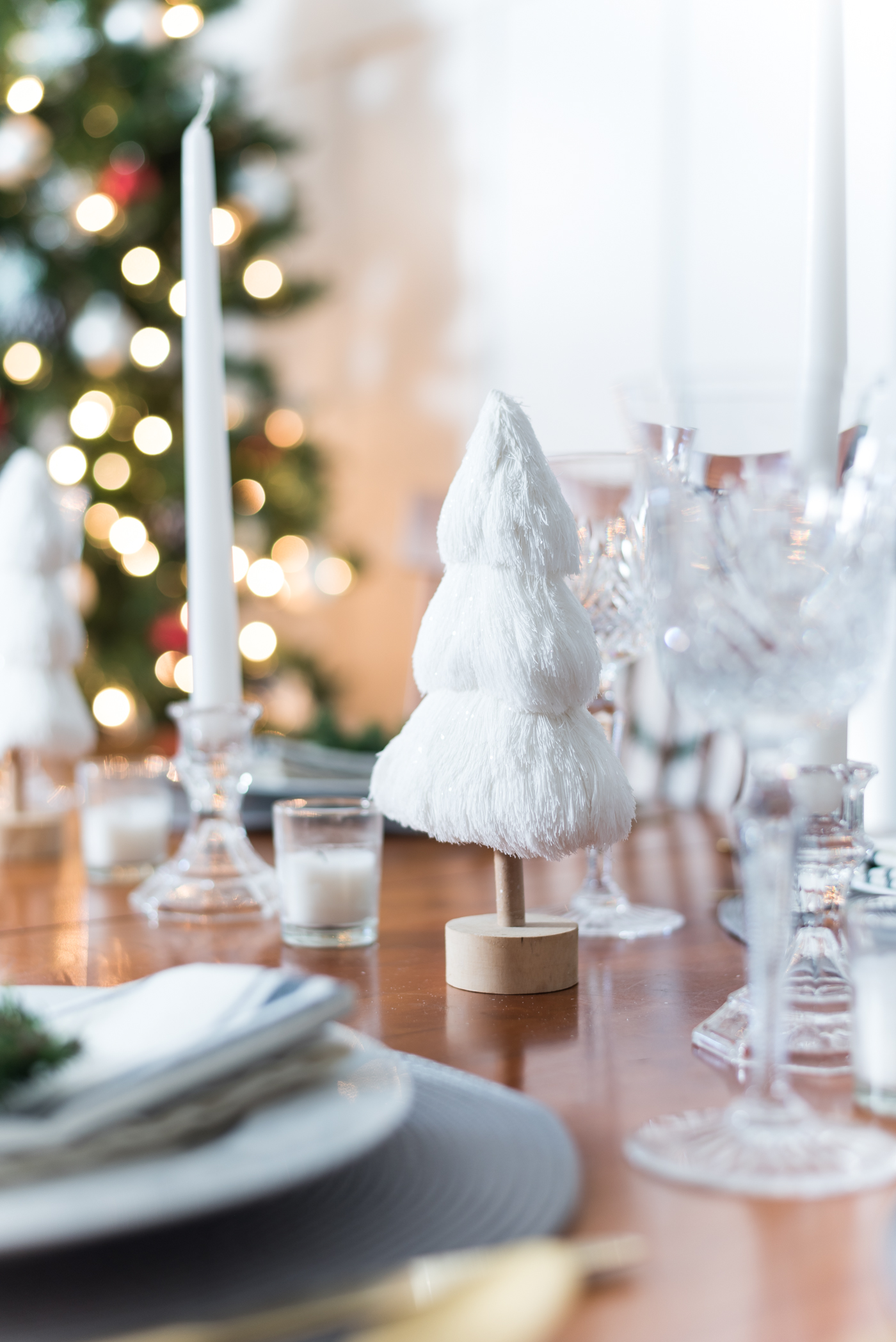 Christmas Table Setting in Gray, White, Gold. Gray and White Holiday Table Setting Idea. Mini Wreath Holiday Place Setting Idea. White mini Christmas Trees and Tapered Candles Holiday Table Centerpiece.