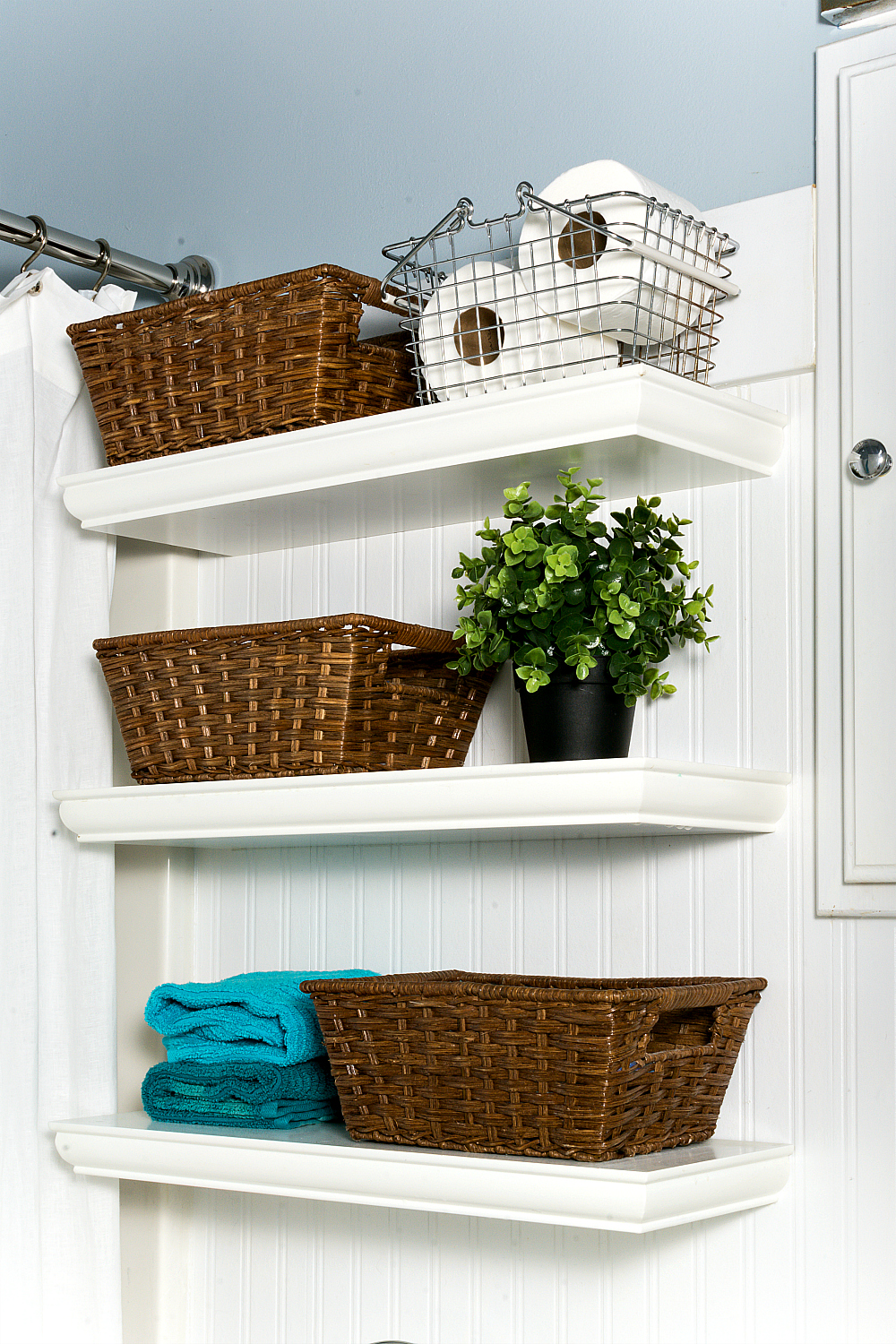 shelves with baskets to organize items. Decorated with faux plants and colorful towels