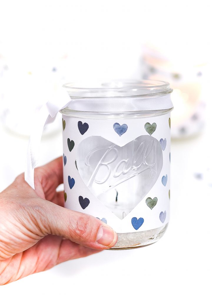 Heart Cut Out Mason Jar Votive - Easy Valentine Craft with Mason Jars, Scrapbook Paper. Scrapbook paper wrapped mason jar with hearts for Valentine's Day. Mason Jar Heart Votive for Valentine's.