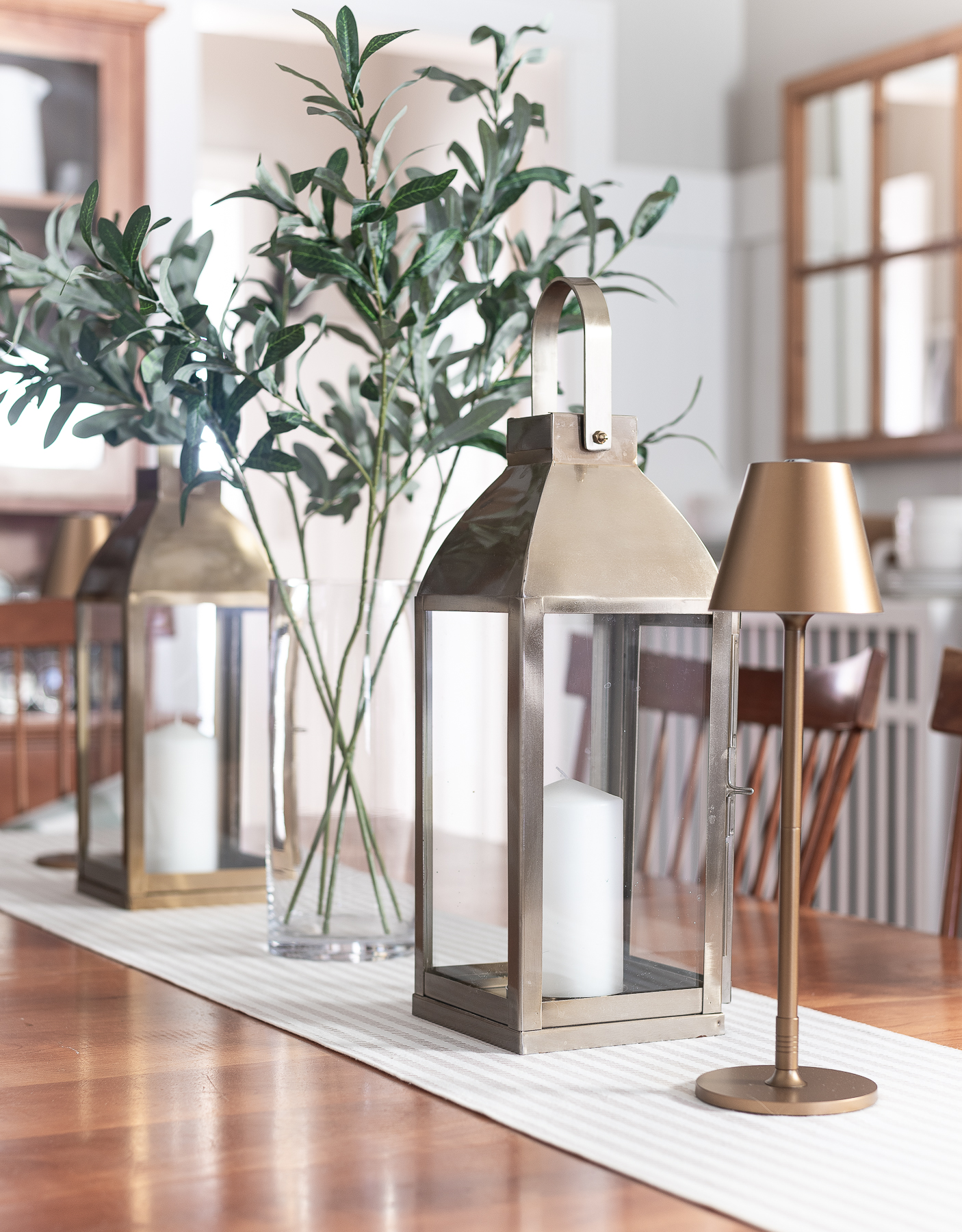 Board and batten dining room - shaker dining room in natural cherry - neutral dining room for spring - tan and white table runner - large gold lanterns - cordless lamps in gold