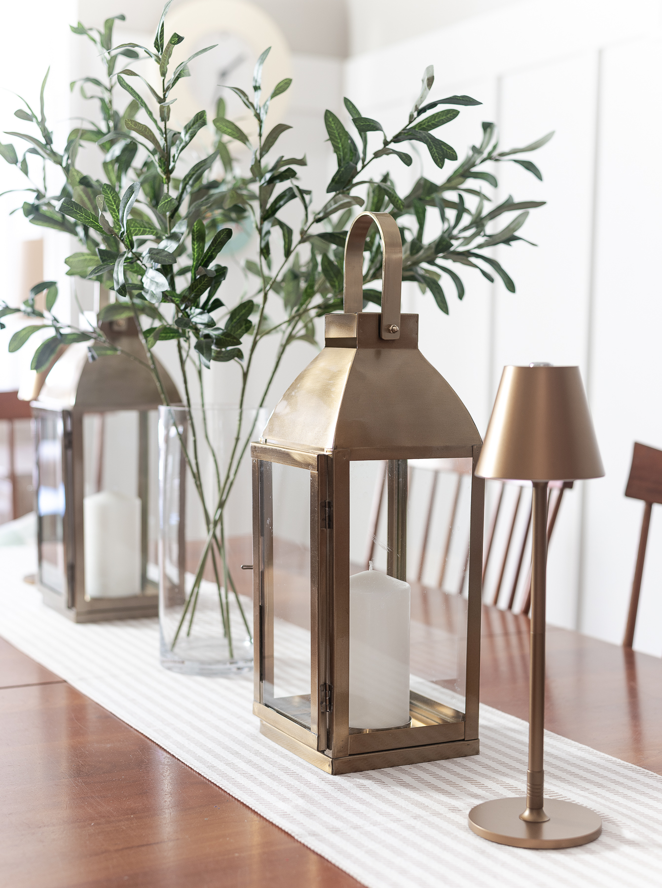 Board and batten dining room - shaker dining room in natural cherry - neutral dining room for spring - tan and white table runner - large gold lanterns - cordless lamps in gold