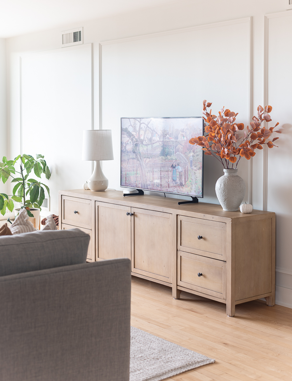 Fall Living Room in Rust, Brown, Mustard, Black, Gray, Neutral. Mustard PIllow. Faux Leather Ottomon from Amazon. Crate & Barrel Barrett Sectional Sofa. Pottery Barn TV Console. Wayfair Side Tables in Light Wood. Vintage Cow Print on Canvas.