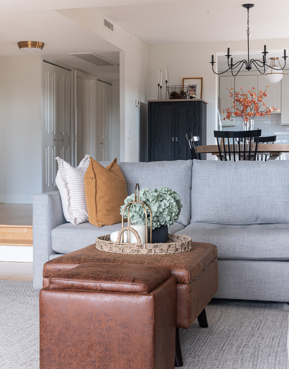 Fall Living Room in Rust, Brown, Mustard, Black, Gray, Neutral. Mustard PIllow. Faux Leather Ottomon from Amazon. Crate & Barrel Barrett Sectional Sofa. Pottery Barn TV Console. Wayfair Side Tables in Light Wood. Vintage Cow Print on Canvas.