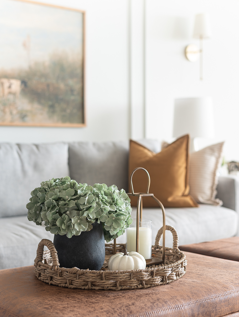 Fall Living Room in Rust, Brown, Mustard, Black, Gray, Neutral. Mustard PIllow. Faux Leather Ottomon from Amazon. Crate & Barrel Barrett Sectional Sofa. Pottery Barn TV Console. Wayfair Side Tables in Light Wood. Vintage Cow Print on Canvas.